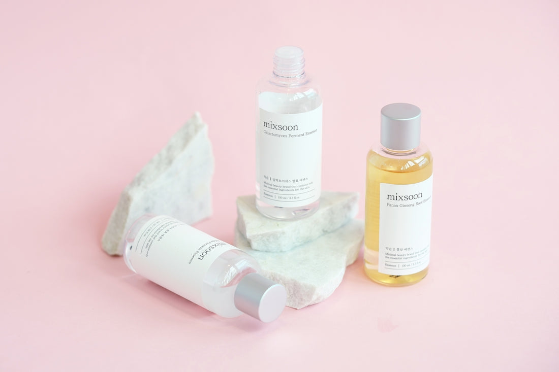 Skincare bottles are displayed on marble rocks.