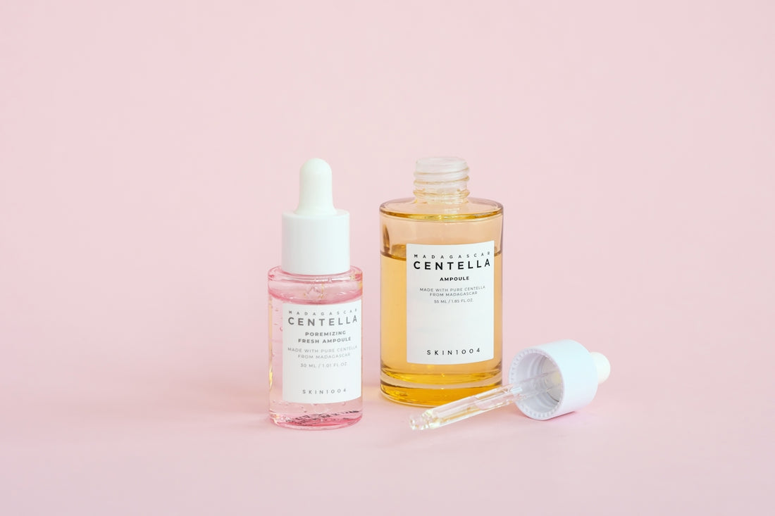 Skincare serums are displayed on a pink background.