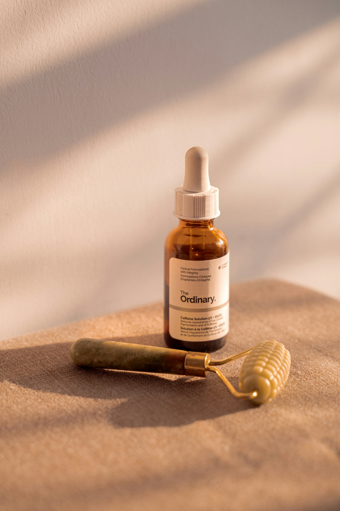 Skincare serum and facial roller on a neutral surface.