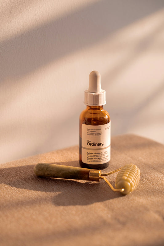 Skincare serum and facial roller on a neutral surface.