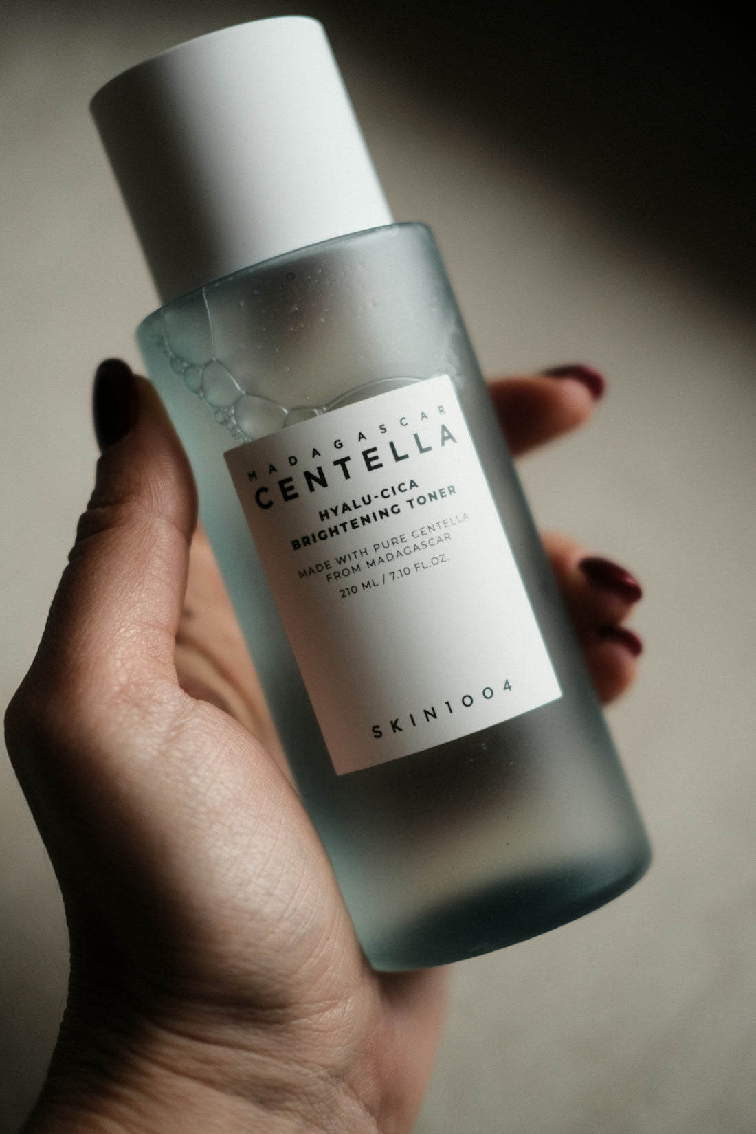 Hand holding a bottle of centella hyalu-cica brightening toner