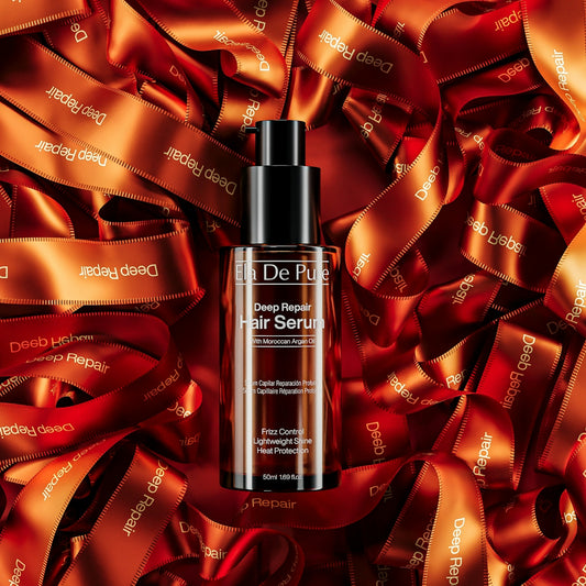 A bottle of hair serum rests on tangled orange ribbons.